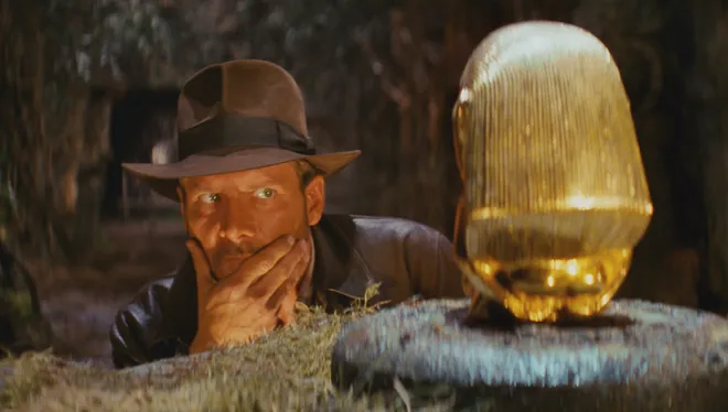 Indiana Jones contemplates how he is going to steal the idol from on top of the platform