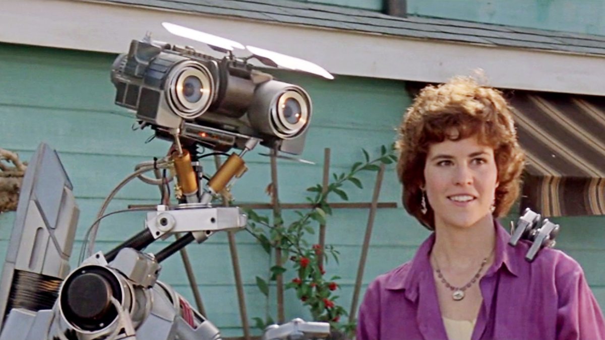 Ally Sheedy standing with the Johnny 5 robot from the movie Short Circuit